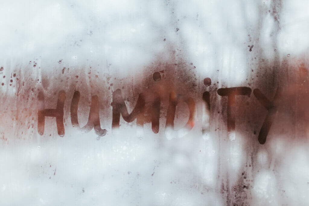 A window covered with moisture due to high humidity within the home. The word humidity is written on the window