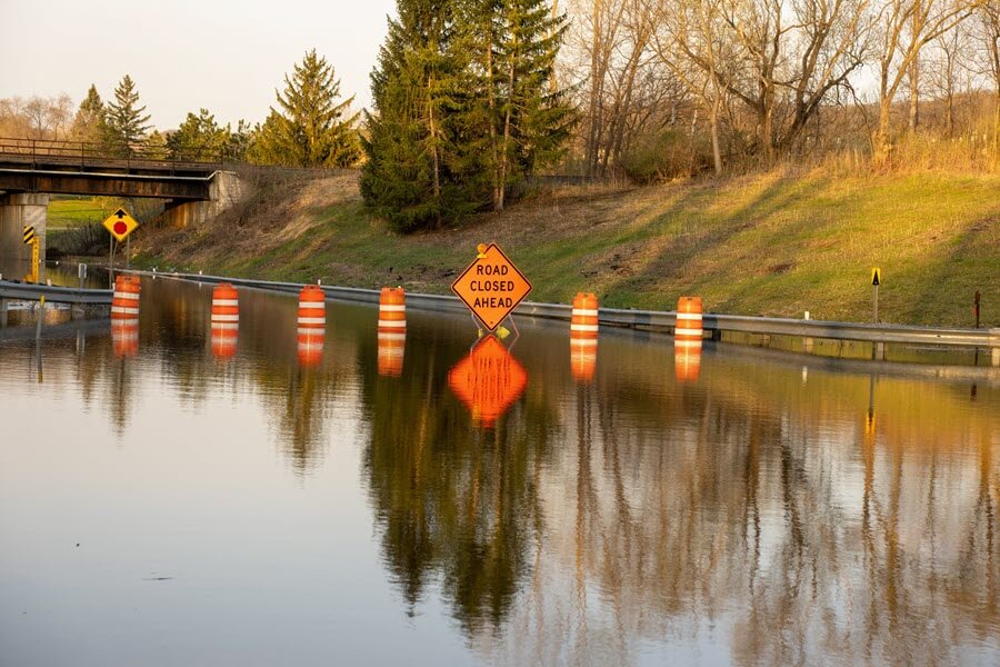 flooded road with "road closed ahead" sign. Example of black water damage