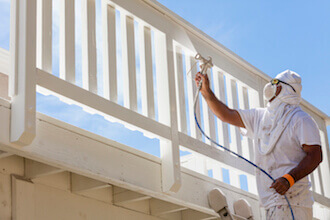 Technician in hazmat suit spraying biostatic inhibitor on wooden railings of a balcony